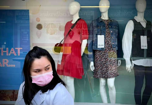 A picture of a woman (wearing a facemask) outside a shop in the Town Centre